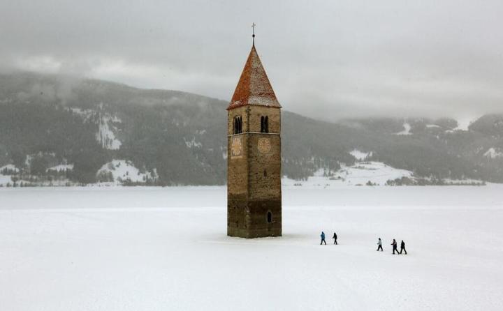 35. A Church steeple pokes out of a frozen lake - Reschen, Italy