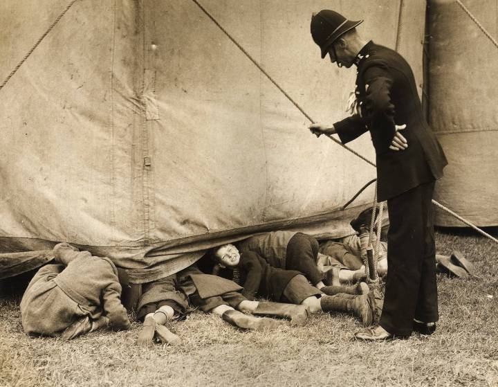 13. A policeman catches a group of boys sneaking a look at the rehearsals of the Bertram Mills Circus in Luton, England, 15th April 1938