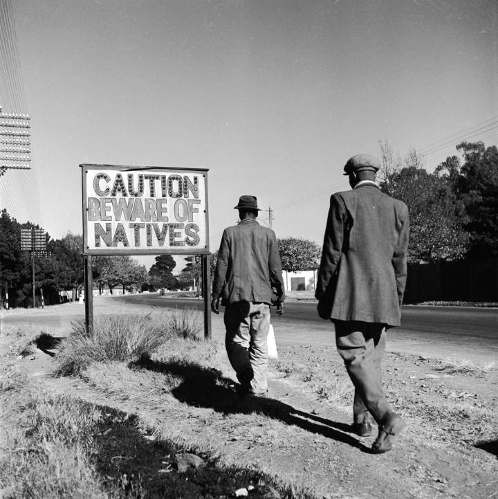 38. Two African men walk past a sign common in apartheid South Africa, Johannesburg, circa 1956