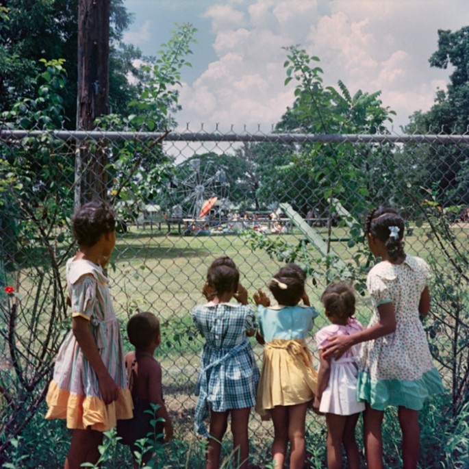 18. Black Children watching as white children play in a whites only park. 1956