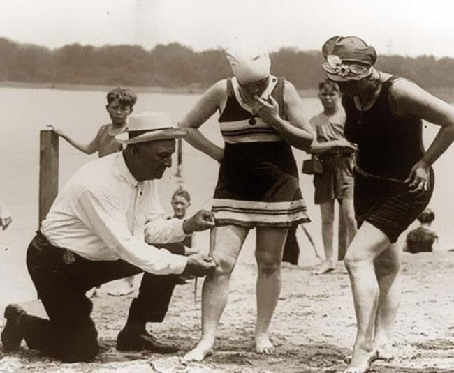 9. A beach official measures bathing suits to ensure they aren't too short (1920s)