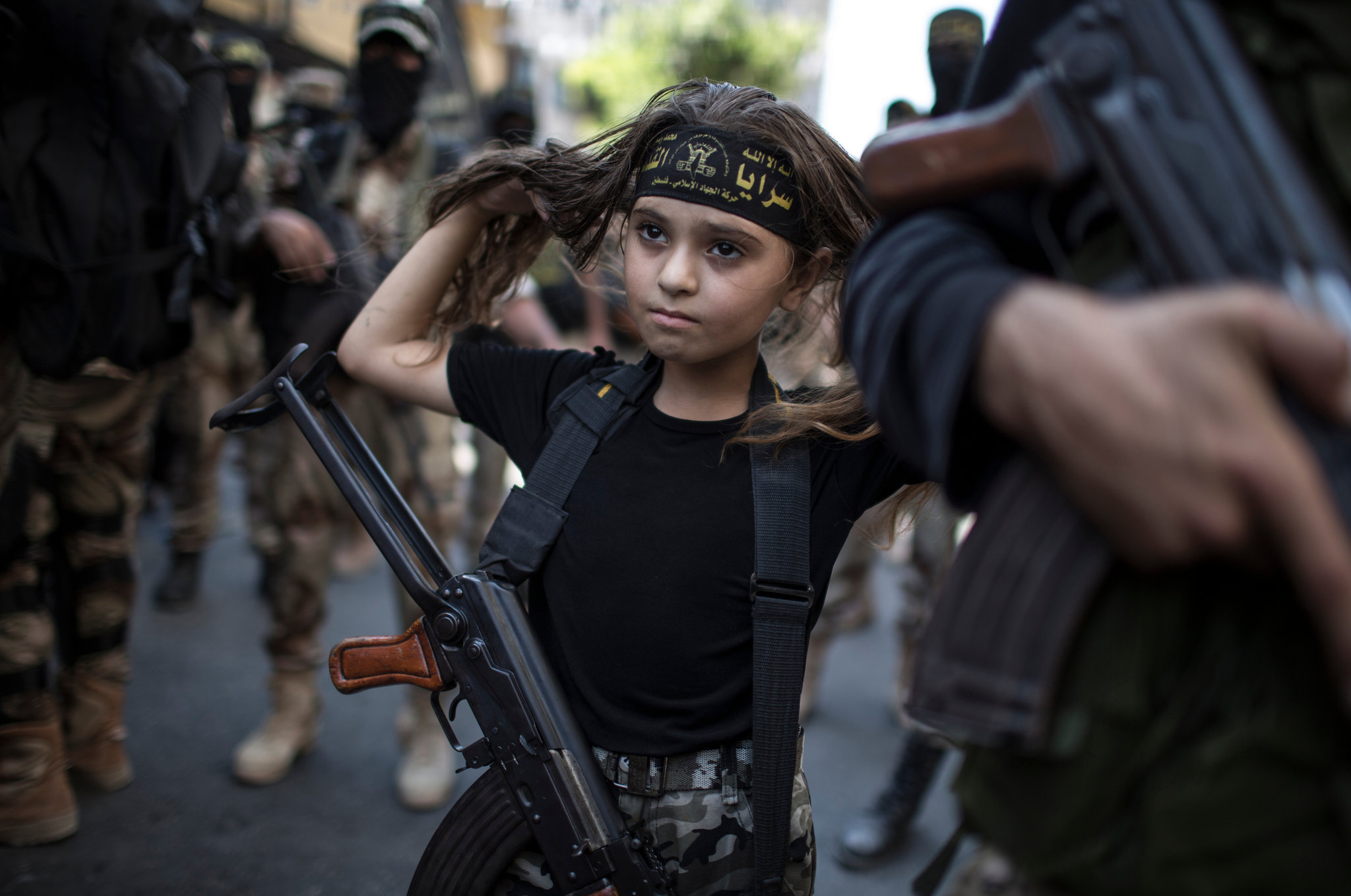 15. A Palestinian girl with a Kalashnikov rifle, amid Islamic Jihad militants in Gaza City