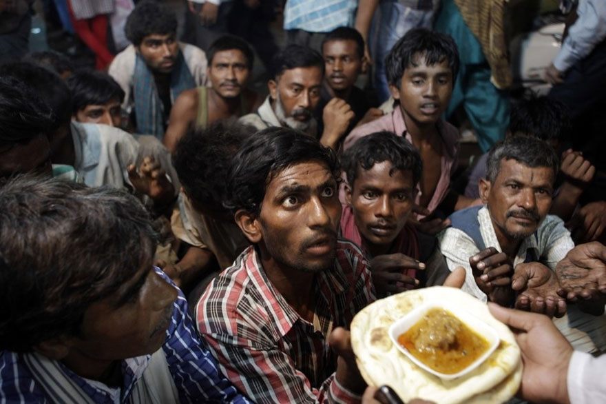 4. Homeless men wait to receive free food distributed outside a mosque ahead of Eid al-Fitr in New Delhi, India